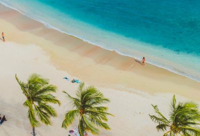 pexels-photo-5007331-5007331 A vibrant tropical beach scene with people, palms, and turquoise waters from above.